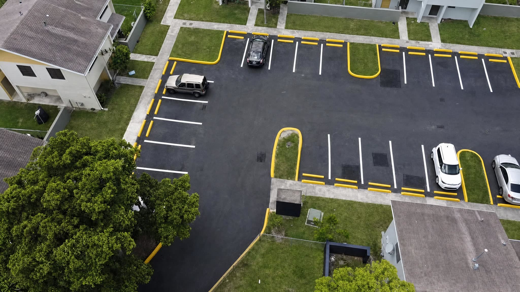 Drone view of a freshly repaved HOA parking lot with new yellow curbs and white stall lines
