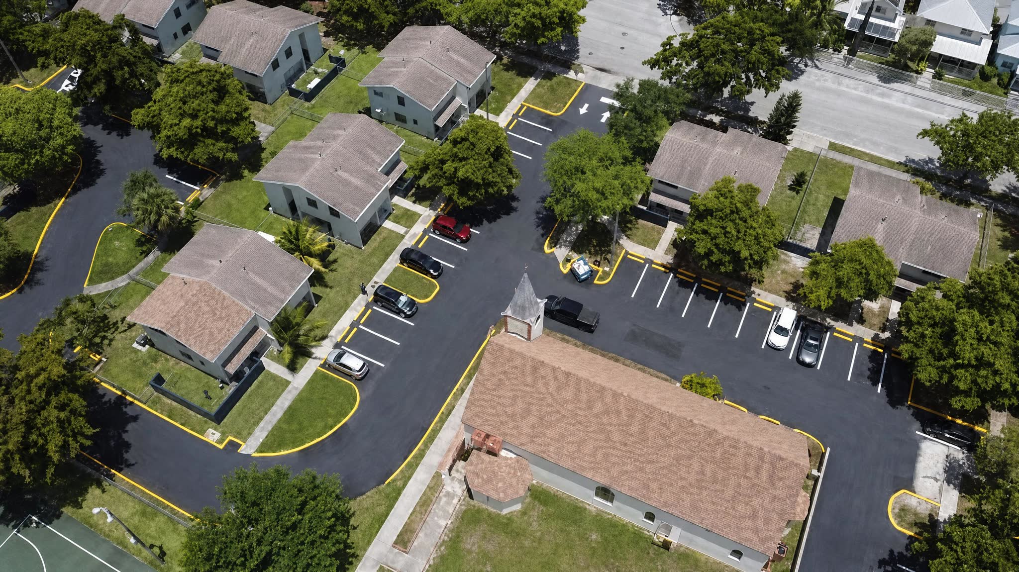 Aerial view of a townhome community with new asphalt lanes, yellow curbs and fresh stall striping
