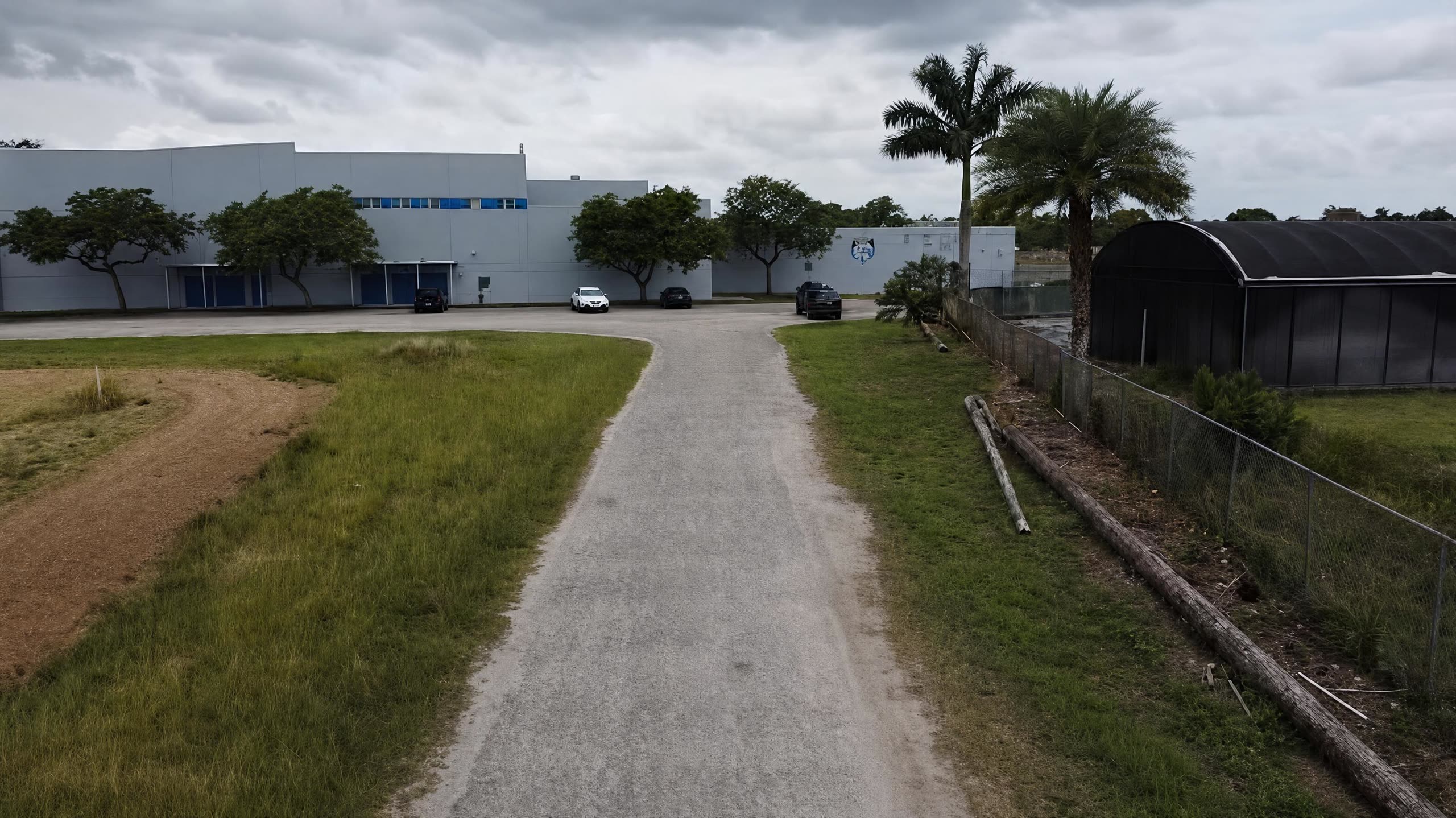 Unpaved gravel access road leading to an industrial facility before construction